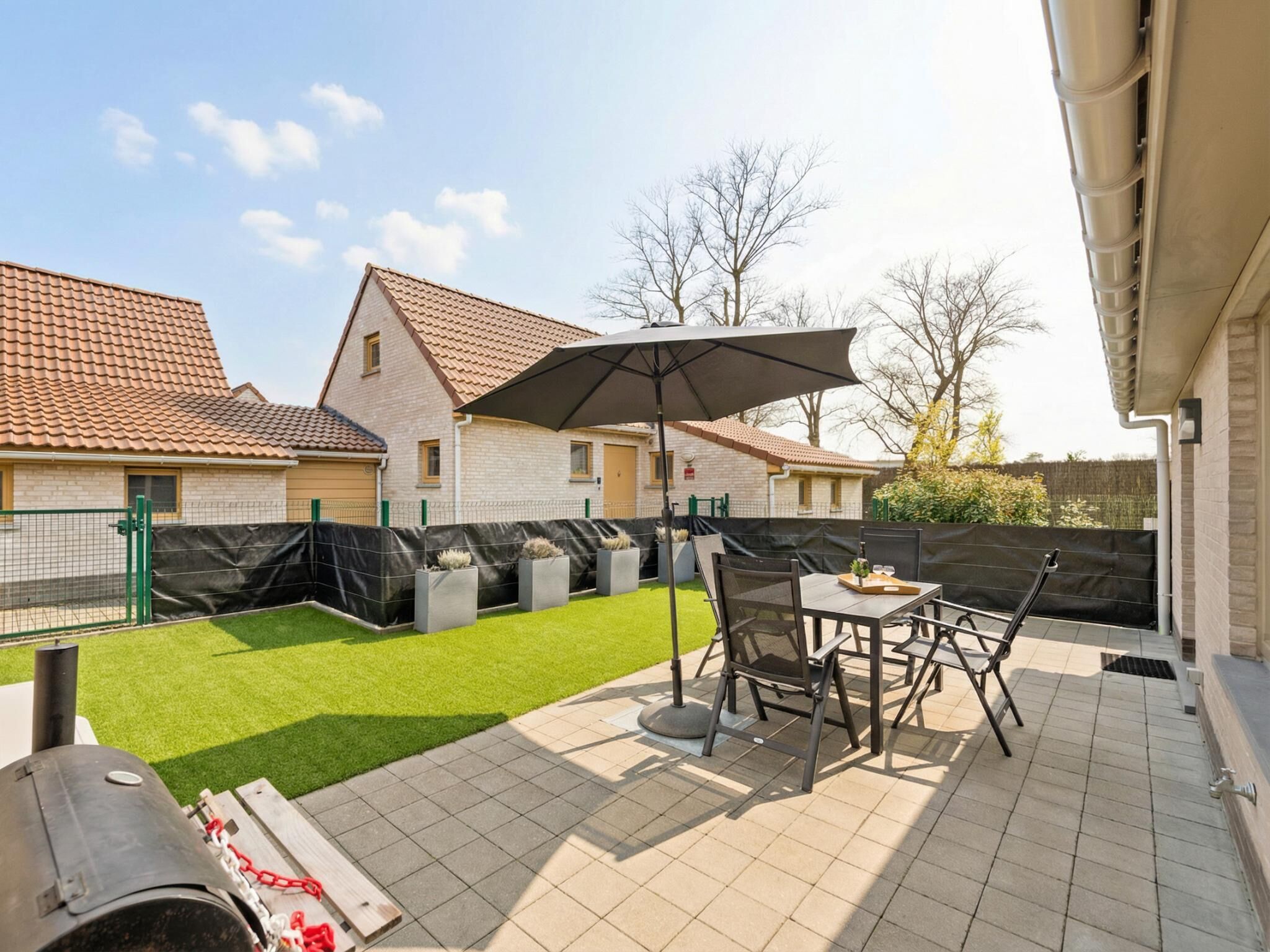 A patio with a table and chairs, a grill, and a covered area with an umbrella.