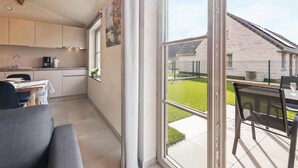 Una cocina moderna con comedor, ventanas amplias y vista a un edificio y jardín.