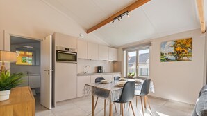 Una cocina moderna con horno, pileta y comedor con sillas y mesa.