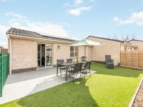 A patio with a table and chairs, a grill, and a fenced yard. - Holiday home on park, pets allowed (Koksijde)