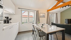 A modern kitchen with a dining area, a TV, and a view of the outside. - Holiday home on park, pets allowed (Koksijde)