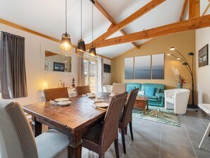 Un comedor con mesa de madera, sillas de mimbre e iluminación colgante.