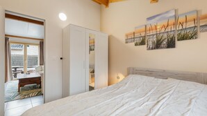 Ein Schlafzimmer mit Bett, Kleiderschrank, Schreibtisch und Ausblick ins Freie.