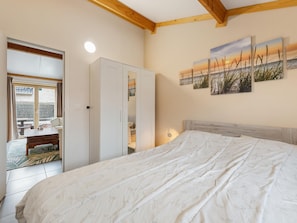 Un dormitorio con cama, armario, escritorio y vistas al exterior.