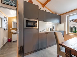 Cocina moderna con armarios grises, microondas integrado y ventana con vistas al exterior.