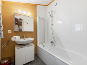 Baño con lavamanos, espejo, ducha y armario.