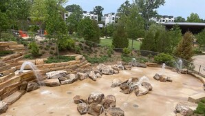 A water feature with multiple streams and rocks, surrounded by a paved area and greenery. - 
Lux Home - Mins to Downtown, RDU, Fenton, UNC Health, WakeMed, & The Triangle (Cary)