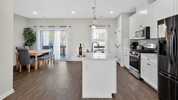 A modern kitchen with white cabinets, stainless steel appliances, and a central island. - 
Lux Home - Mins to Downtown, RDU, Fenton, UNC Health, WakeMed, & The Triangle (Cary)