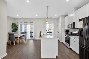 A modern kitchen with white cabinets, stainless steel appliances, and a central island.