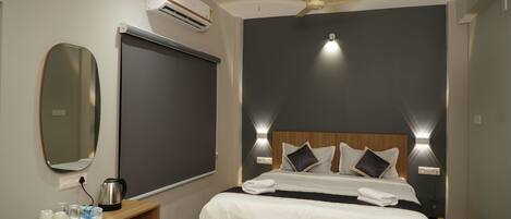 A modern hotel room with a bed, bedside tables, a mirror, and a ceiling fan.