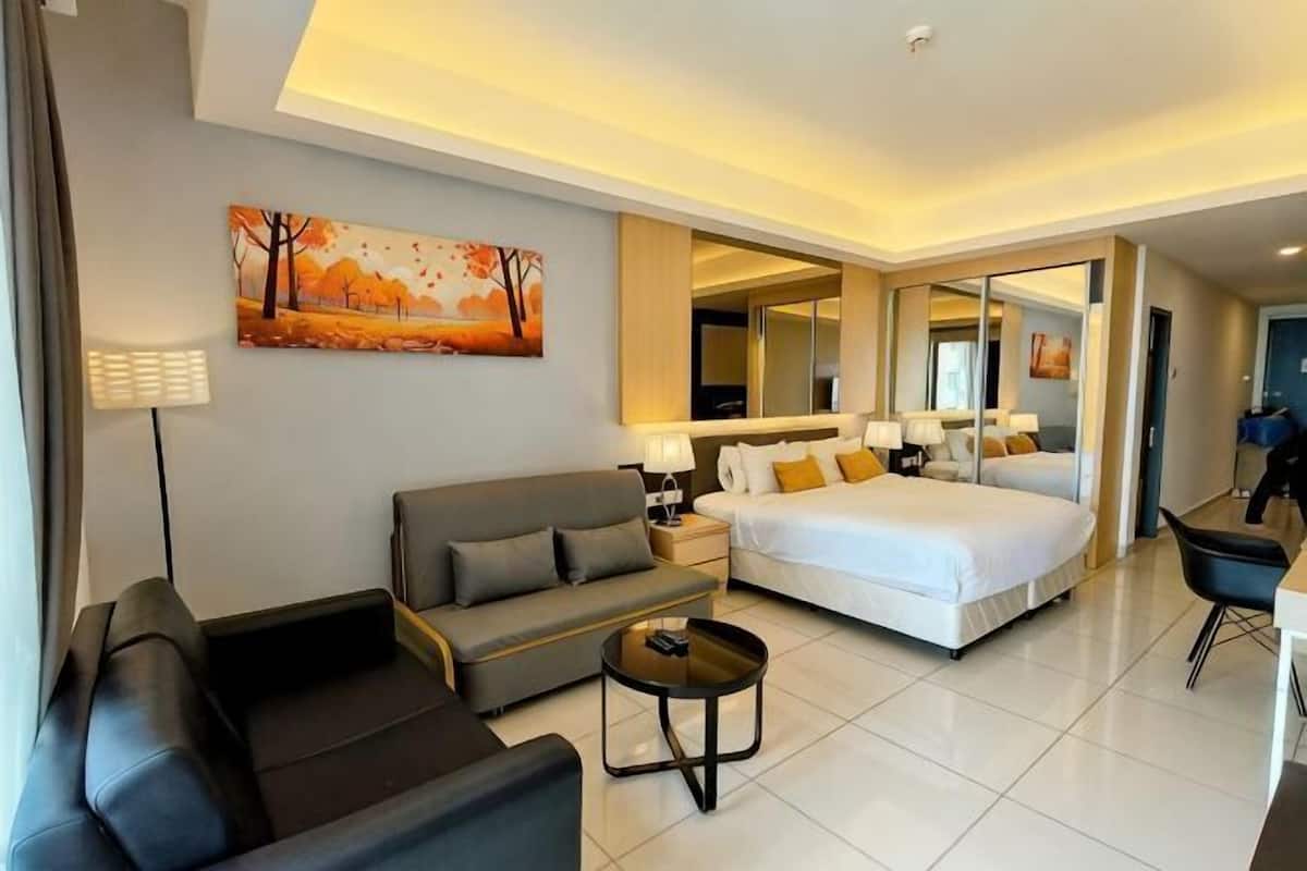 A hotel room with a bed, a sofa, a coffee table, and a desk with a chair.