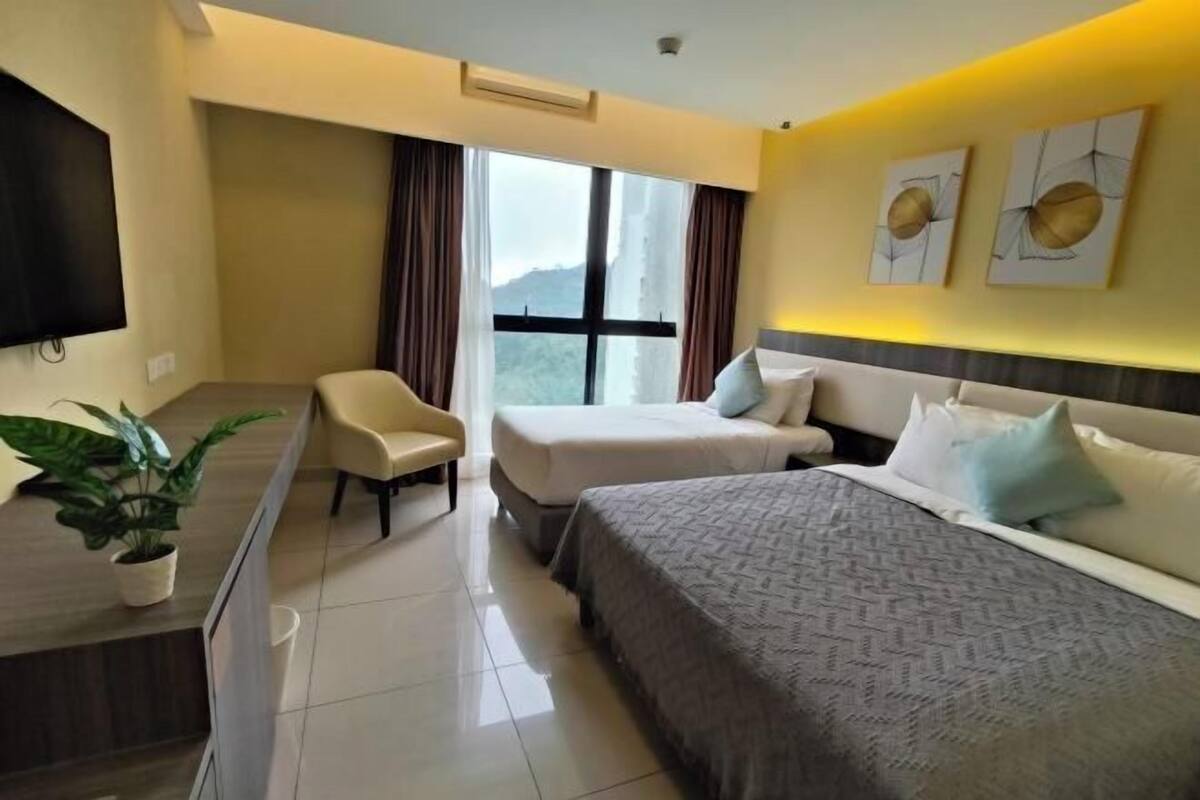 A hotel room with two beds, a desk, a chair, a large window, and artwork on the wall.