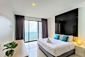 A modern hotel room with a large bed, a nightstand, a potted plant, and a view of the city through large windows. - Emerald Homes Cozy Homestay @ Genting Highlands (Genting Highlands)