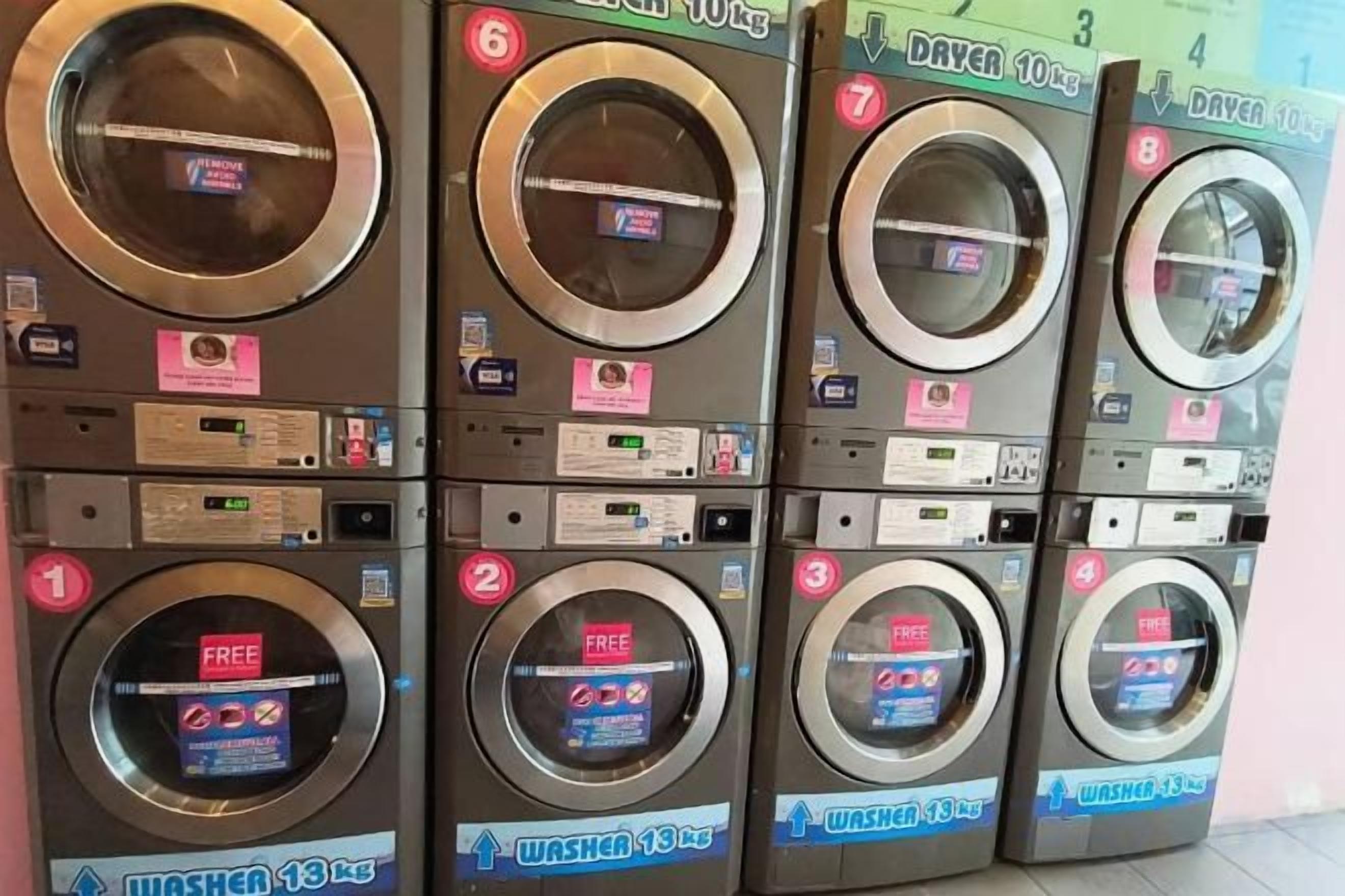 A row of six stacked laundry machines with labels and instructions.