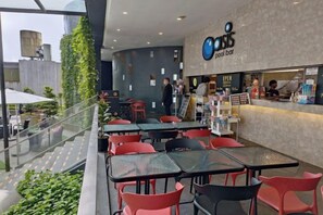 An outdoor seating area with tables and chairs, a pool bar, and a view of the cityscape. - Emerald Homes Cozy Homestay @ Genting Highlands (Genting Highlands)