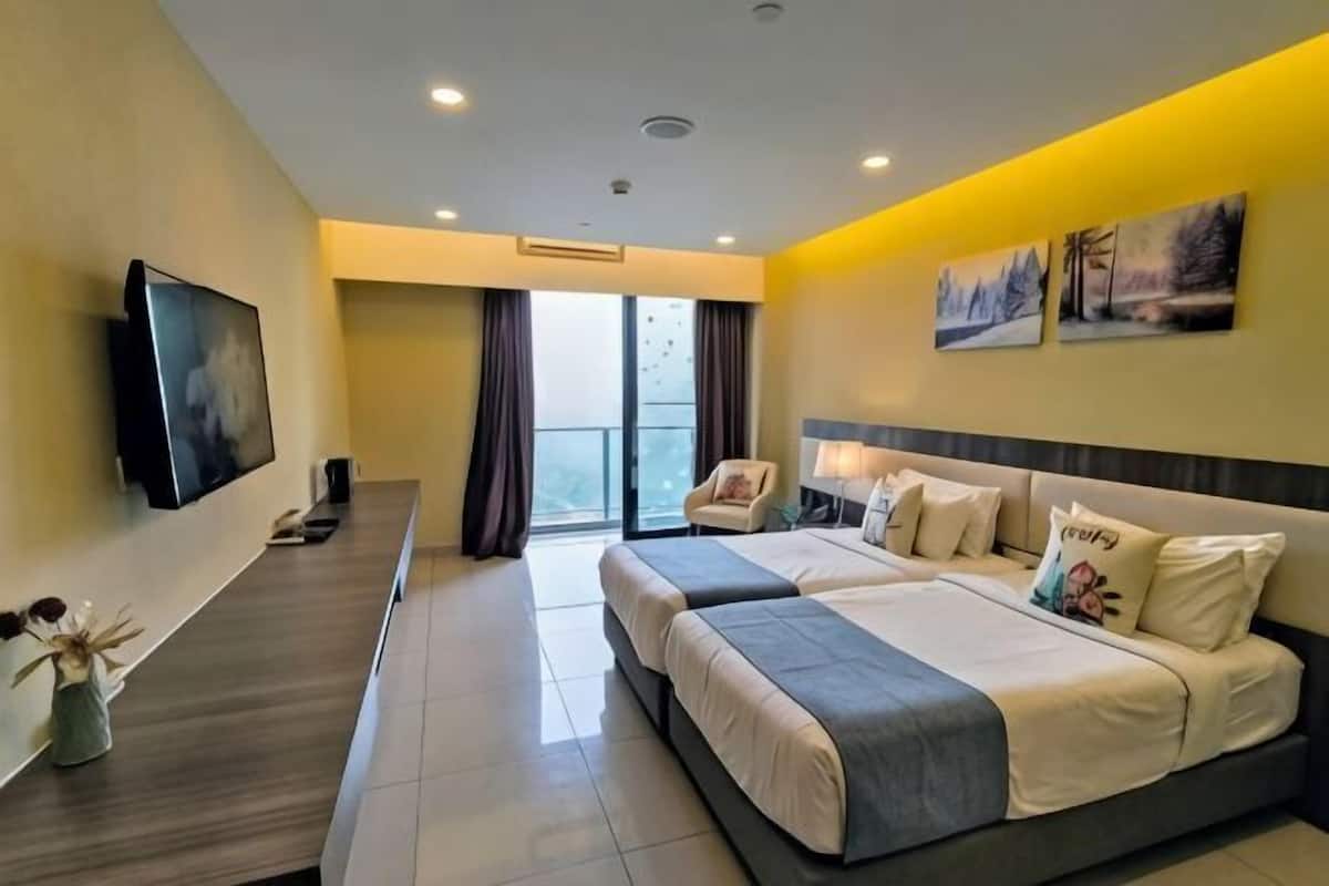 A hotel room with two beds, a TV, a desk, and a balcony with curtains.