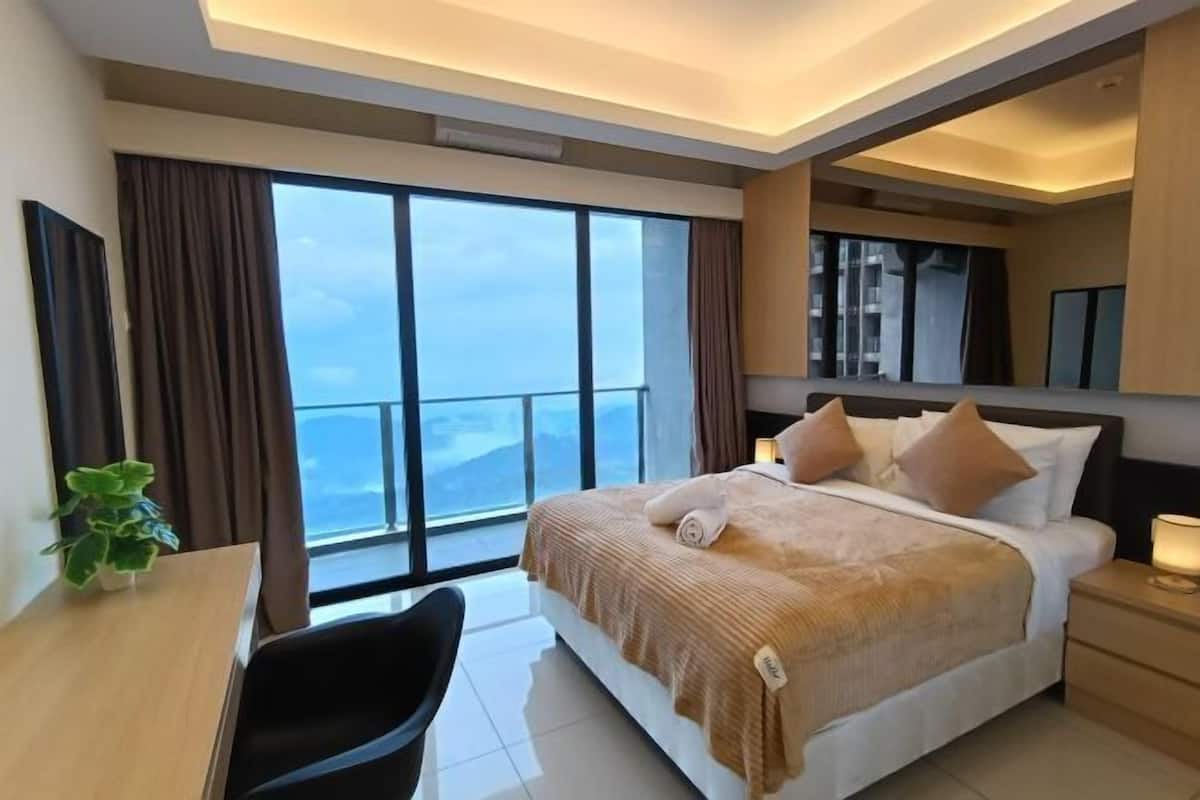 A modern hotel room with a large bed, a desk, and a view of the city.