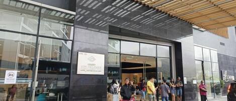 A modern building with a covered entrance, large glass windows, and a sign indicating a restaurant.