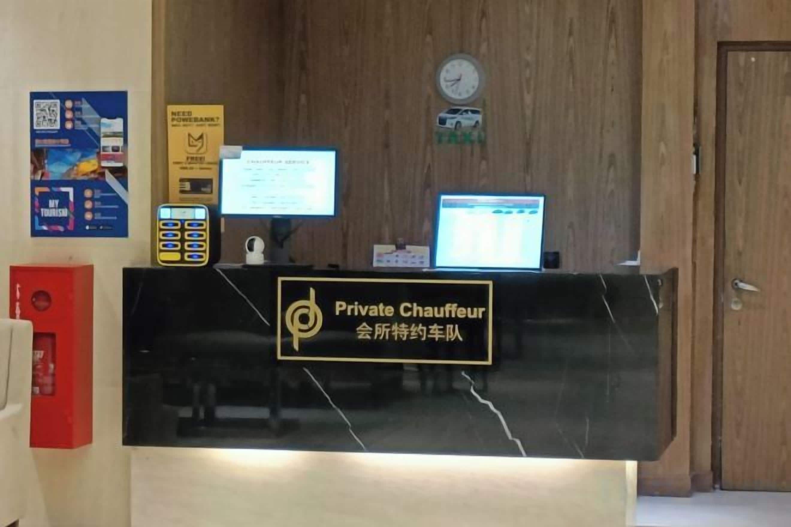 A reception desk with a sign reading 'Private Chauffeur' and a computer monitor.
