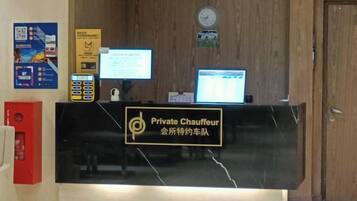 Un mostrador de recepción con un letrero que dice 'Private Chauffeur' y un monitor de computadora.