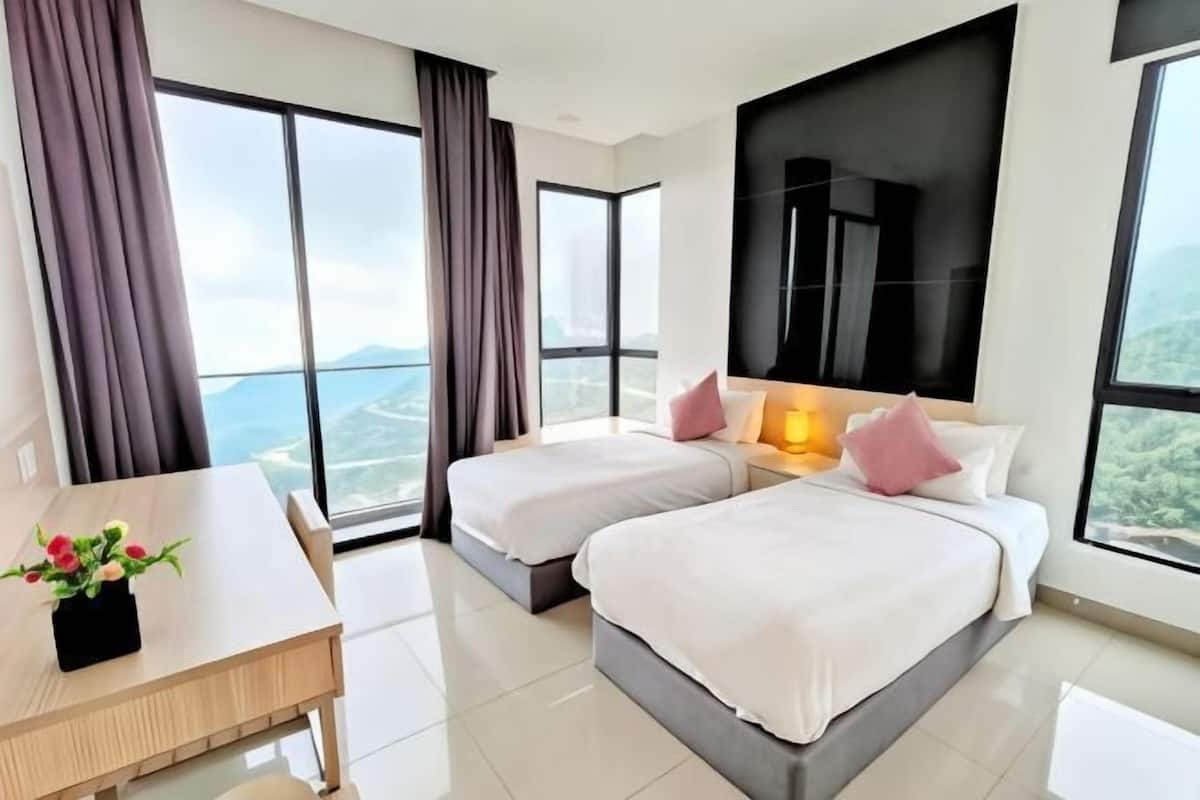 A hotel room with two beds, a desk, and large windows offering a view.