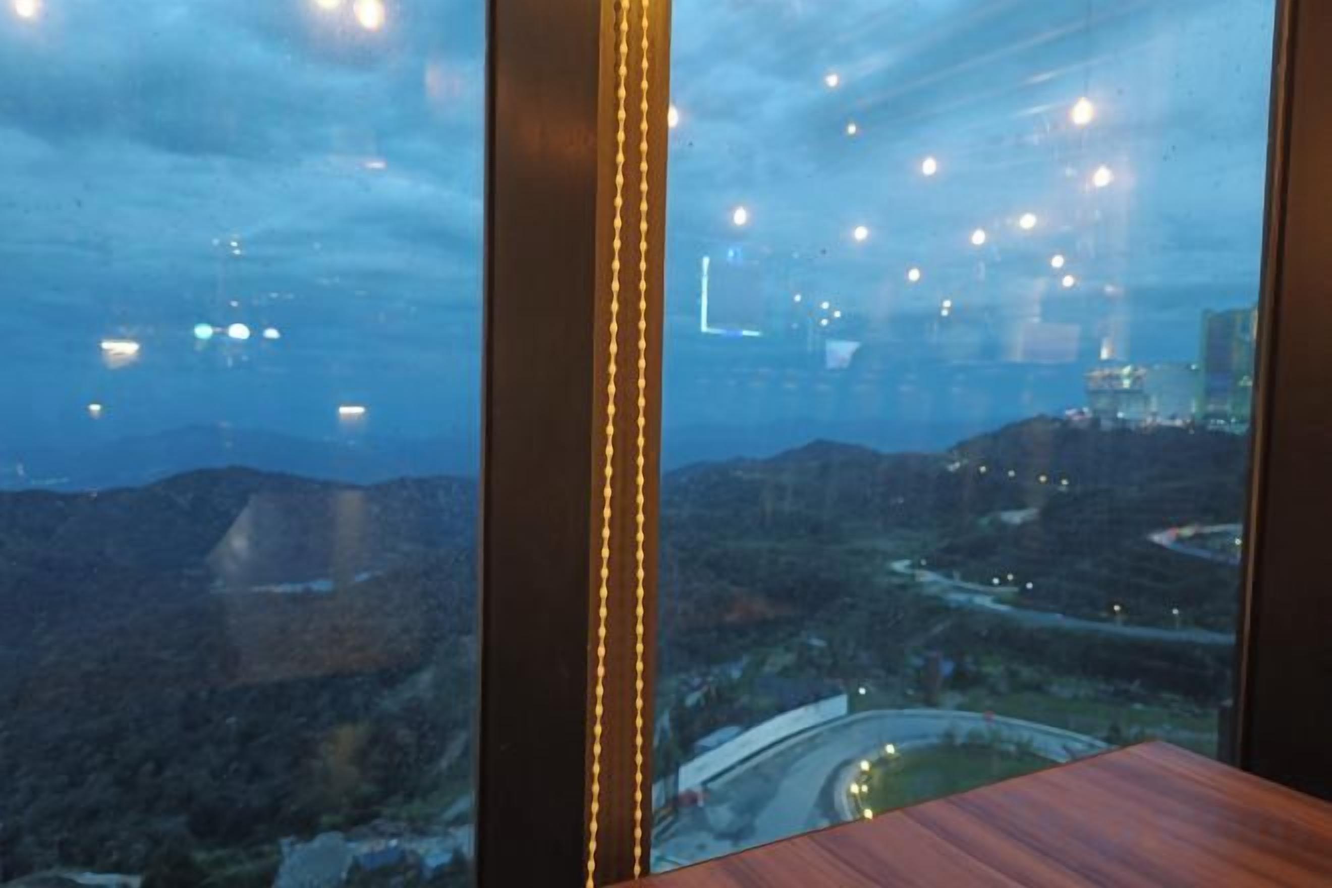 A room with a large window overlooking a mountainous landscape and a road.