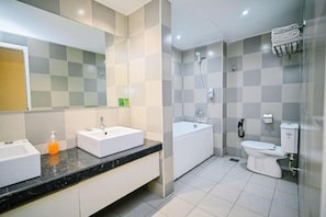 A modern bathroom with a large mirror, two sinks, a bathtub, and a toilet. - Kingston Hotel 1 @ Bukit Bintang (Kuala Lumpur)