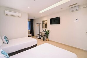 A hotel room with two beds, a desk, a chair, a TV, and an air conditioning unit. - Kingston Hotel 1 @ Bukit Bintang (Kuala Lumpur)