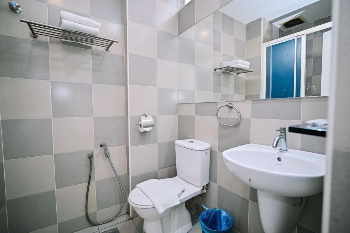 Un baño con inodoro, lavamanos, ducha y toallero.