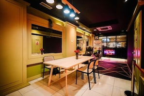A restaurant with a table and chairs, a neon sign, and a door. - Kingston Hotel 1 @ Bukit Bintang (Kuala Lumpur)