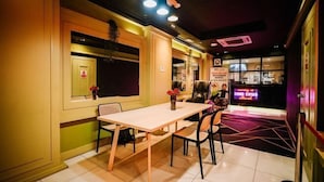 A conference room with a table and chairs, a window with a view, and a neon sign in the background. - Kingston Hotel 1 @ Bukit Bintang (Kuala Lumpur)