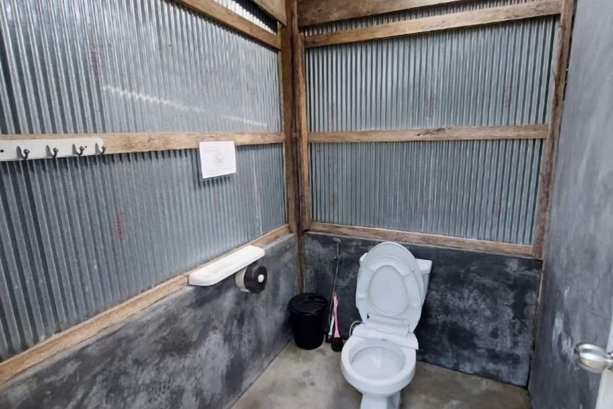 Un baño pequeño y cerrado con un inodoro, un lavabo y un cubo negro.