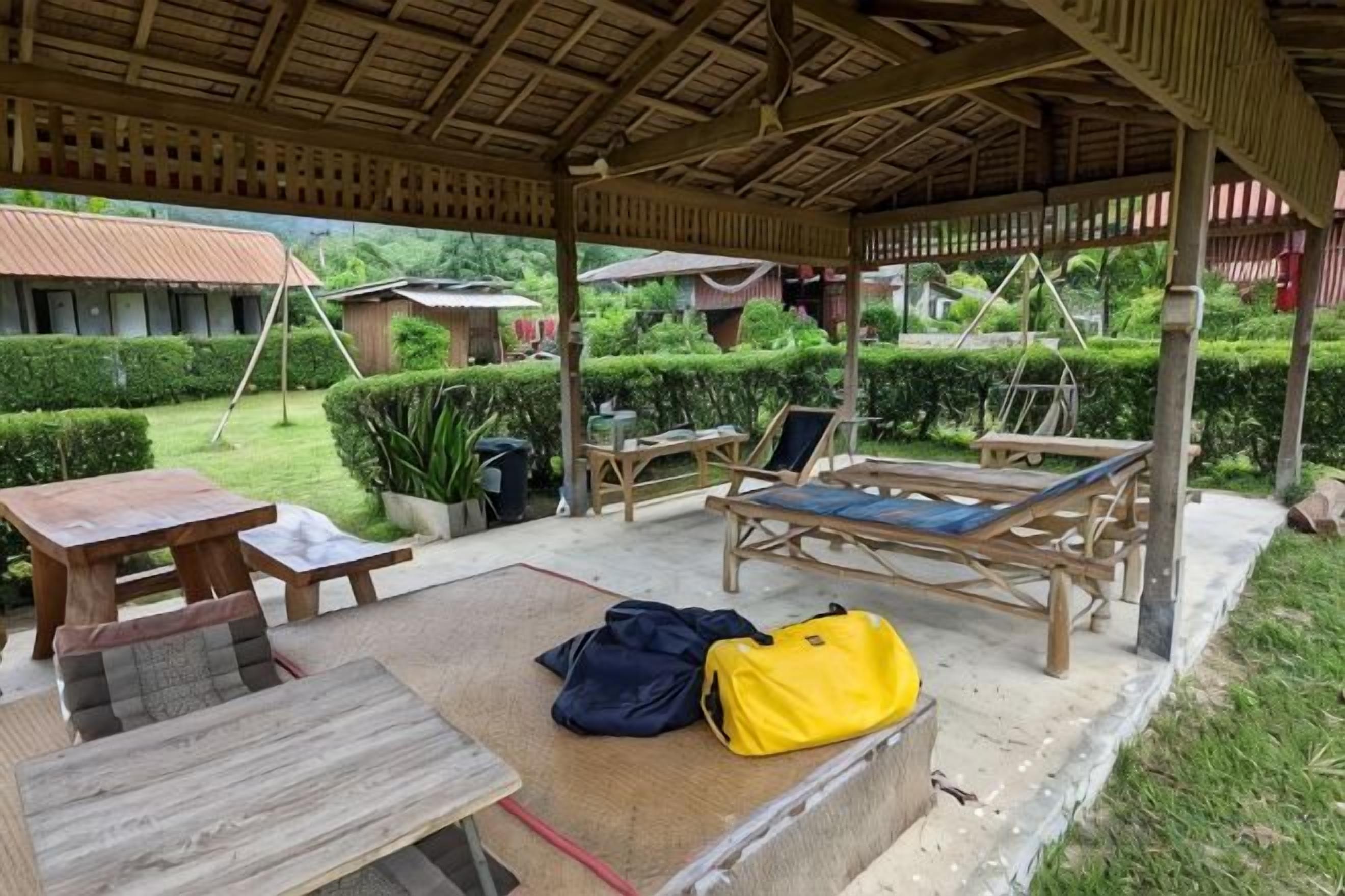 Un área de estar al aire libre con techo, una mesa, sillas y una tumbona.