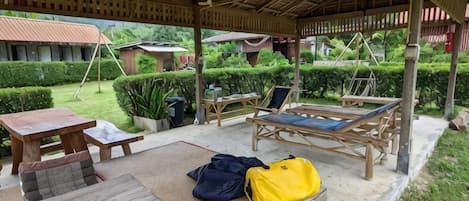 An outdoor covered seating area with a table, chairs, and a lounge chair.