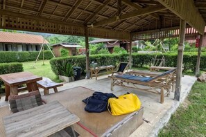 An outdoor covered seating area with a table, chairs, and a lounge chair. - Samui Camping Farm (Koh Samui)