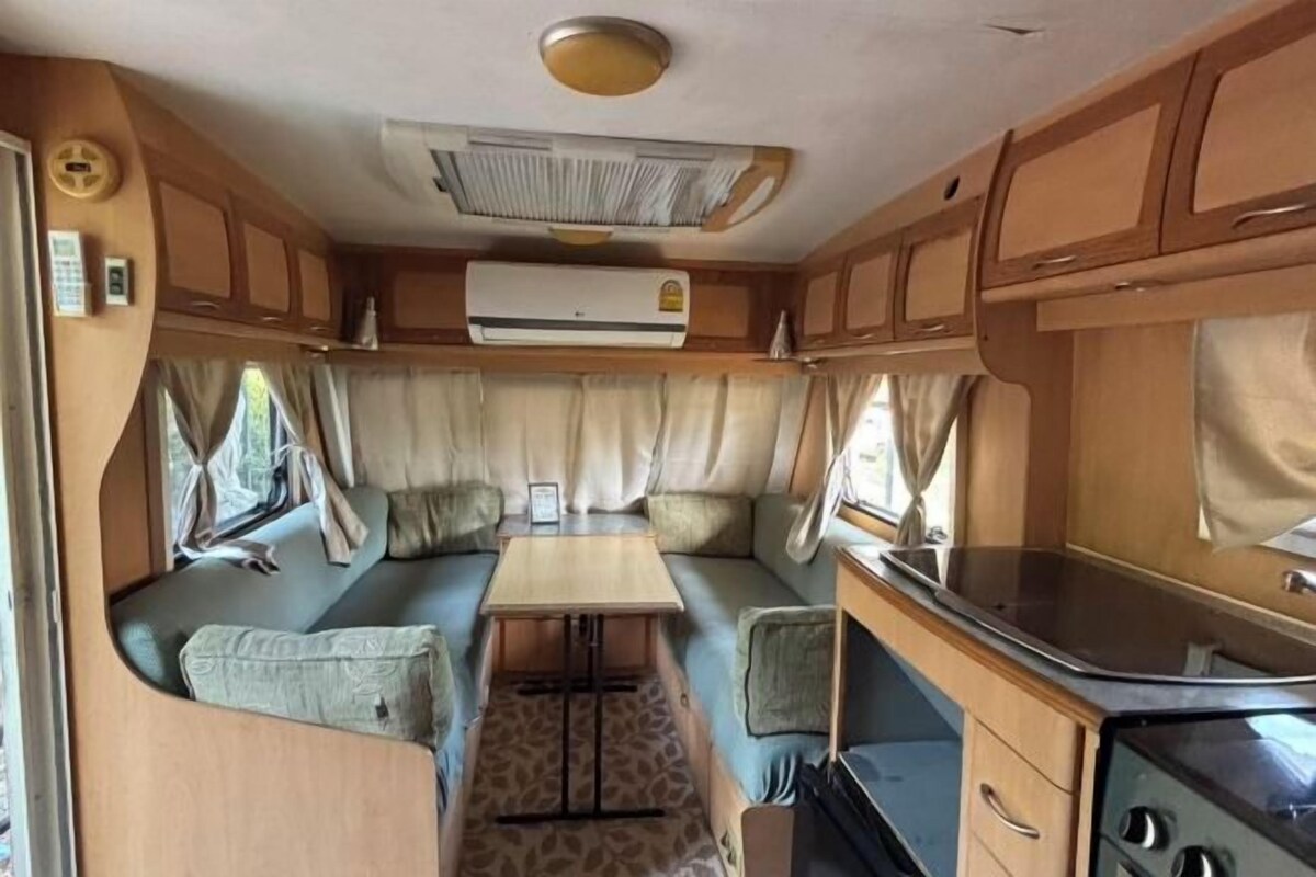 A compact RV interior with a kitchenette, a dining area, and a sleeping berth.