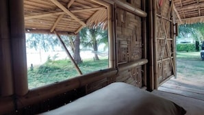 A room with a thatched roof, wooden walls, and a window overlooking a garden. - Samui Camping Farm (Koh Samui)