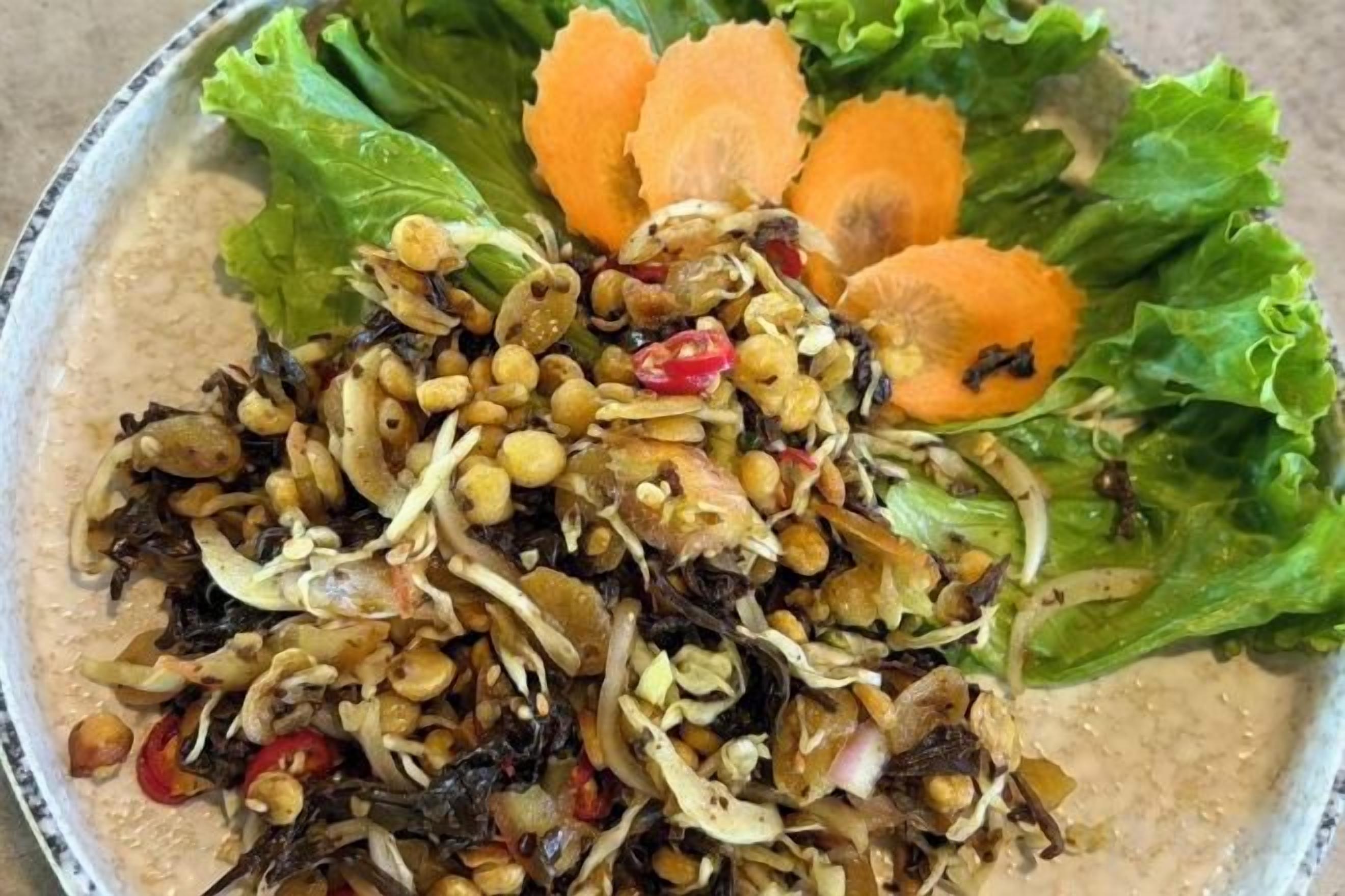 Un tazón de ensalada con diversas verduras y garbanzos.