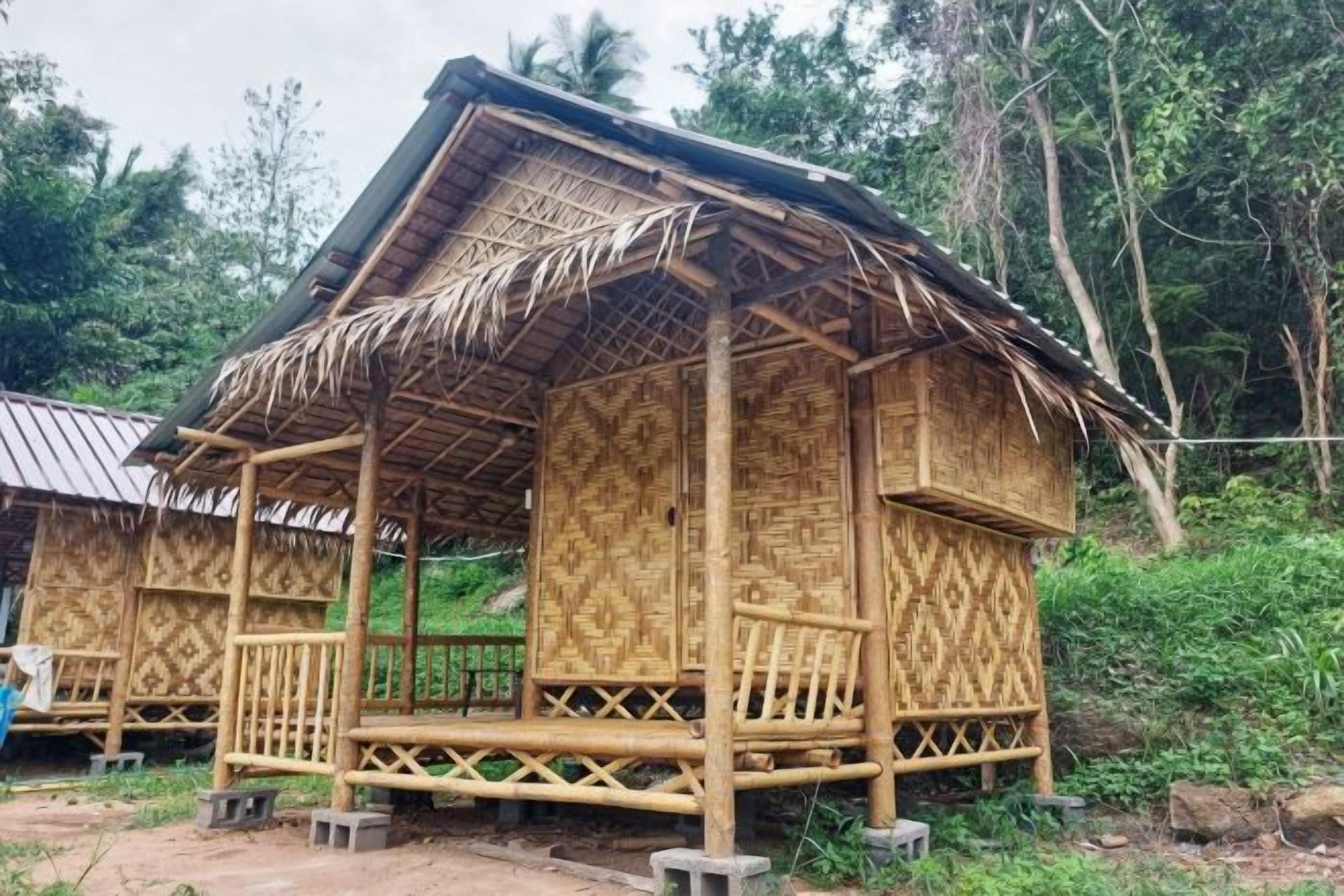 Una cabaña de bambú con techo de paja, un porche y un diseño de celosía.