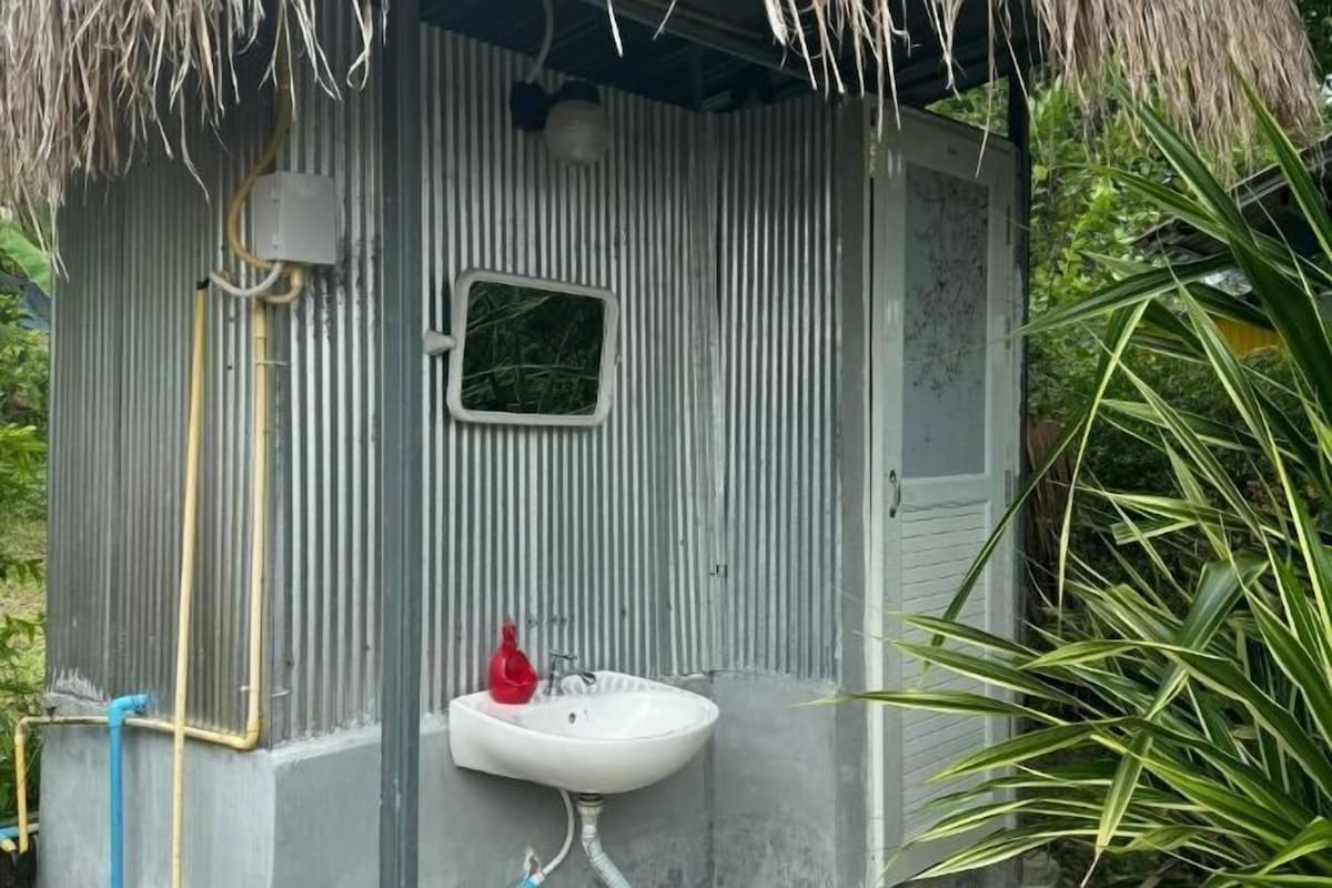 A compact bathroom with a sink, a mirror, and a shower area.