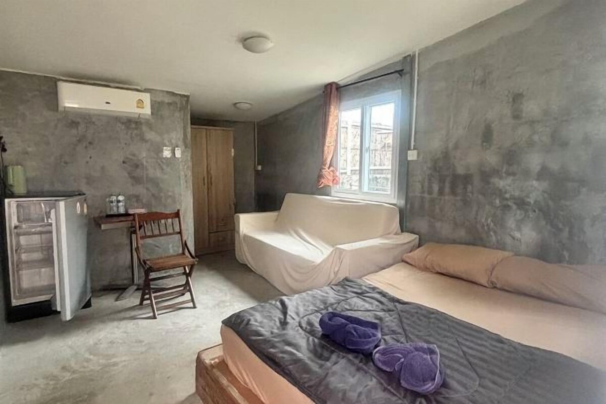 A room with a bed, a small table, a chair, a wardrobe, and a window with curtains.