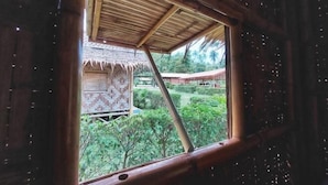 A room with a wooden ceiling and a window overlooking a garden with a thatched-roof structure. - Samui Camping Farm (Koh Samui)