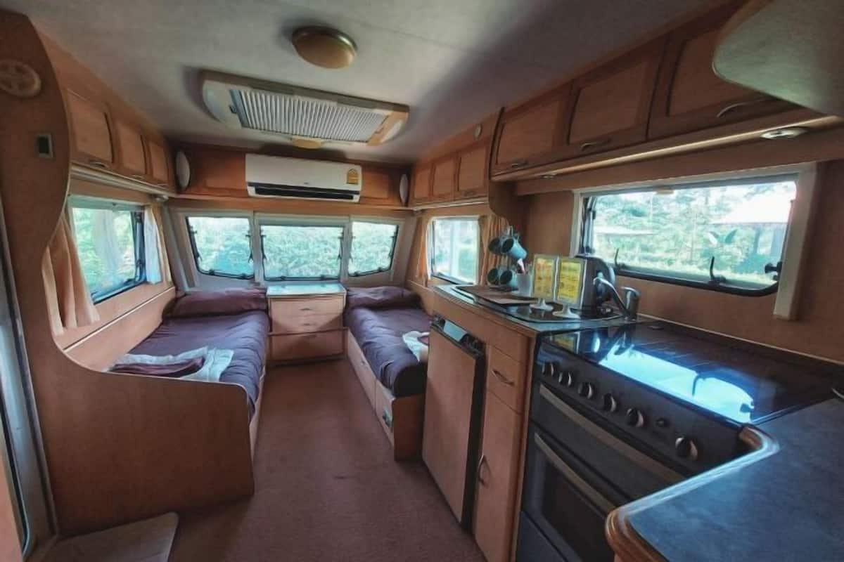 Interior compacto de autocaravana con kitchenette, comedor y litera.