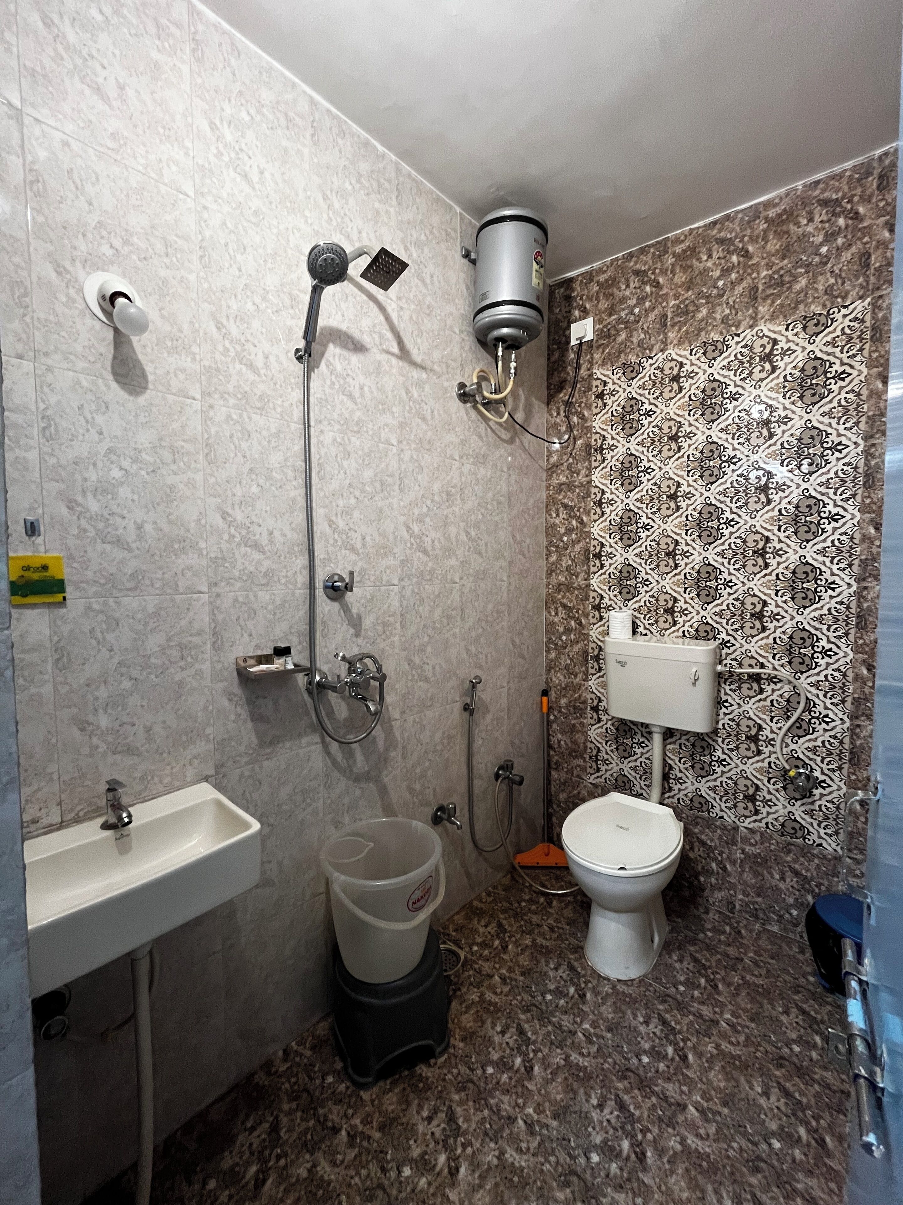 A bathroom with a sink, toilet, shower, and a patterned wall.