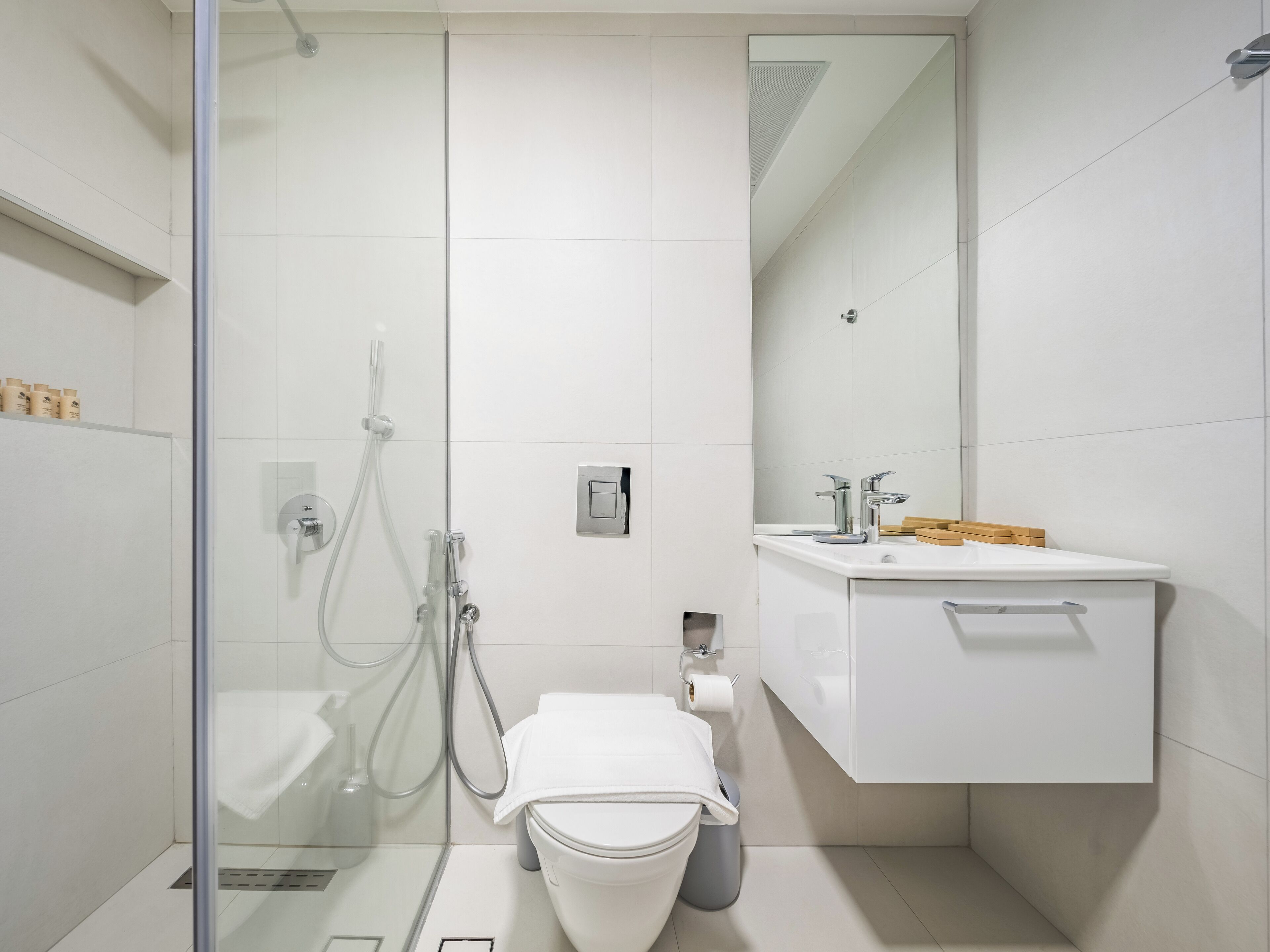 A modern bathroom with a glass-enclosed shower, a white toilet, and a sink with a mirror.