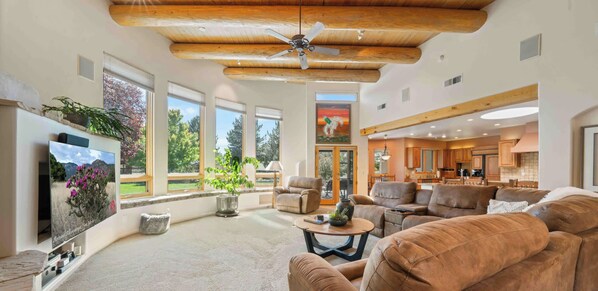 A spacious living room with a large window, a ceiling fan, and a view of the outdoors.