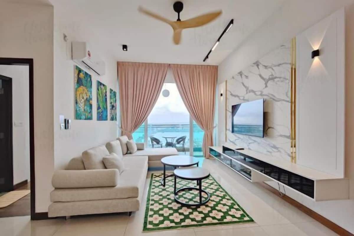 Un salon moderne avec un canapé, un téléviseur, un ventilateur de plafond et une vue sur la mer.