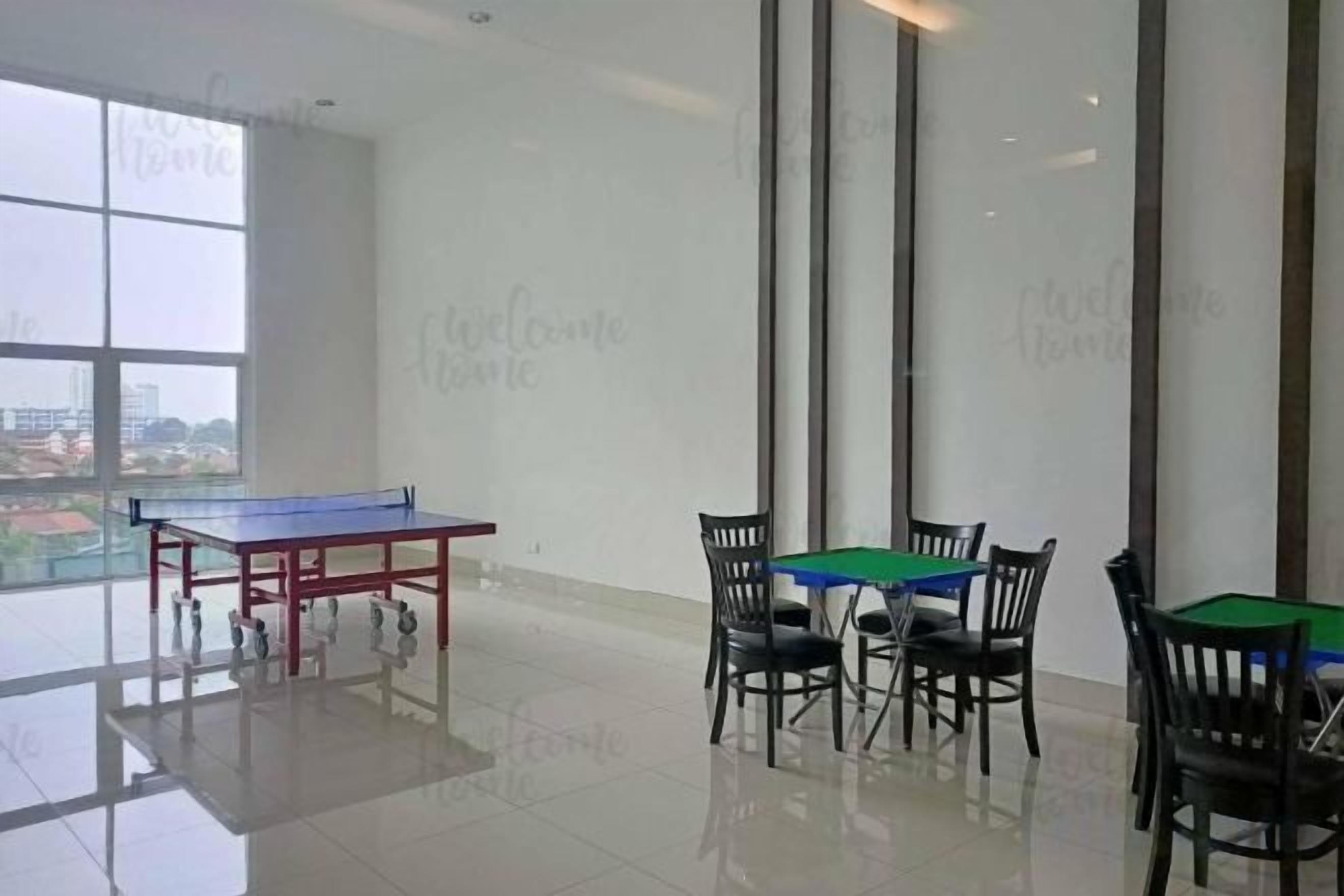 A spacious room with a ping pong table, four chairs, and a view of a cityscape through large windows.