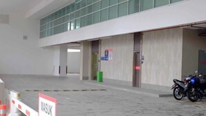 Un espace de stationnement avec une moto, un panneau indiquant « ENTRÉE », et l’entrée d’un bâtiment avec des portes en verre.