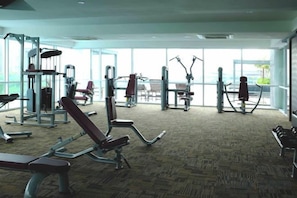 A gym with various exercise equipment, large windows, and a carpeted floor. - Paragon Suites CIQ Homestay by WELCOME HOME (Johor Bahru)